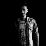 Black and white portrait of a man in a denim jacket captured dramatically.